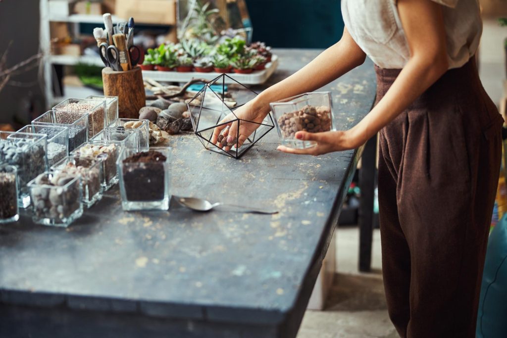 florist-with-a-glass-vase-leaning-over-black counter