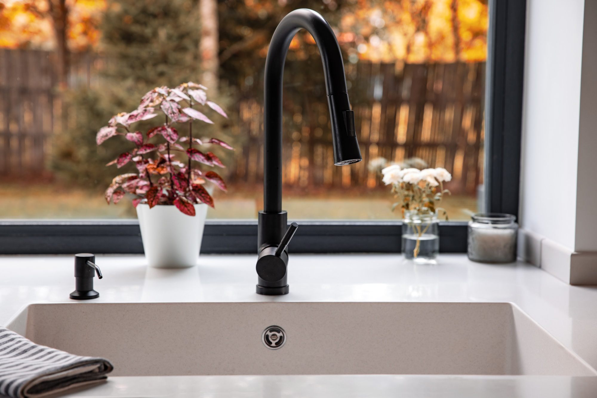 Modern White Kitchen Sink with black Stainless Steel faucet, bright window with fall autumn season.